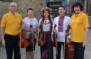Photo of 5 musicians holding string instruments. 2 people in yellow. 3 people in Ukrainian national dress. 